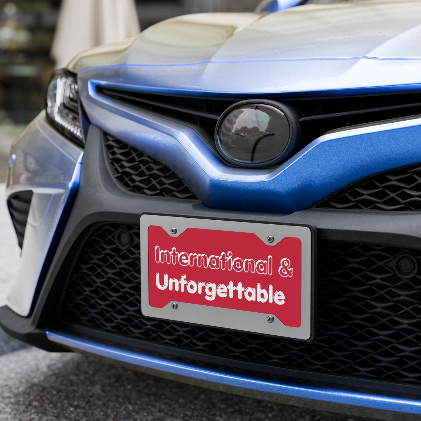 Close-up of a car's front grille with a red license plate reading 'International & Unforgettable'. - Laureles Internacionales Vanity License Plate - Serendipitous Landing