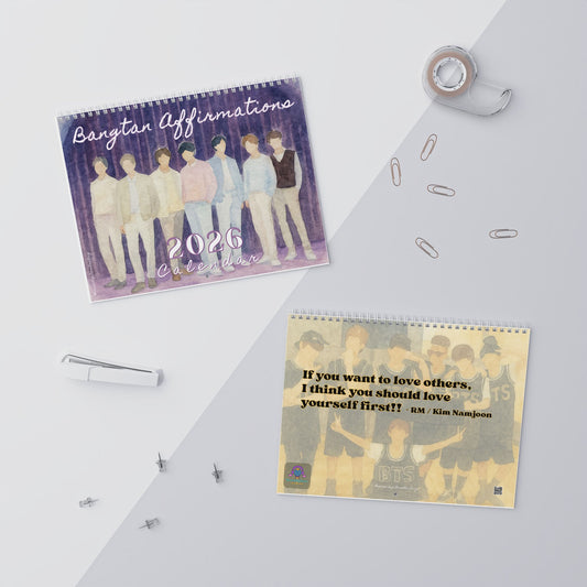 Two calendars on a white surface with office supplies. - BTS 2026 Wall Calendar - Bangtan Affirmations, OT7 Watercolor Art | Monthly Song Recommendations