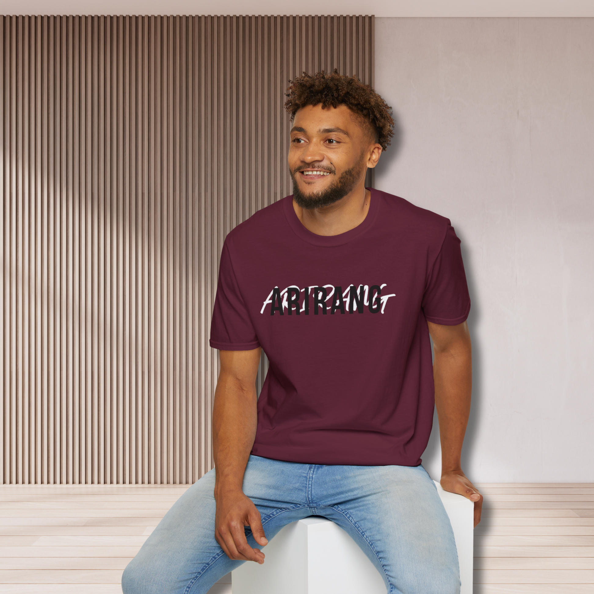 Man wearing a maroon t-shirt with 'ARIRANG' text, sitting on a white stool against a neutral wall - Bangtan 2026 Unofficial Shirt [Bias Arirang Color Vinyl Edition], OT7- Jimin, Burgundy
