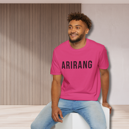 Man wearing a pink t-shirt with 'ARIRANG' text sitting on a white stool against a neutral wall. - Bangtan Tour 2026 Unofficial Shirt [Bias Arirang Color Vinyl Edition, Simple Text] - Jin, Pink, Seokjin