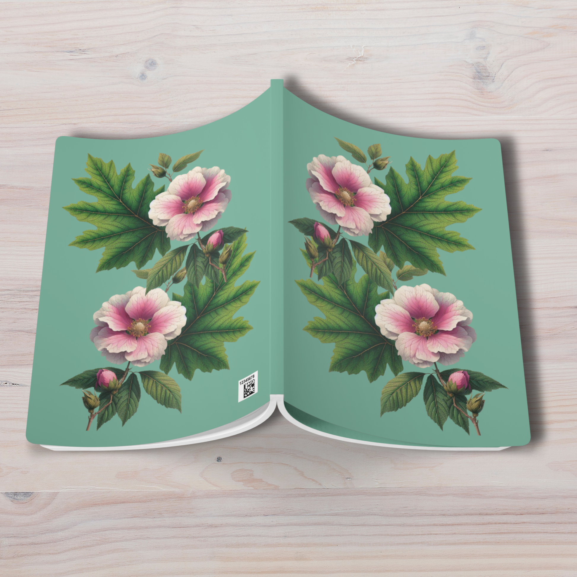 Book with floral design on a light wooden surface - mugunghwa and oak leaf botanical design - teal / sage green cover, perforated notebook