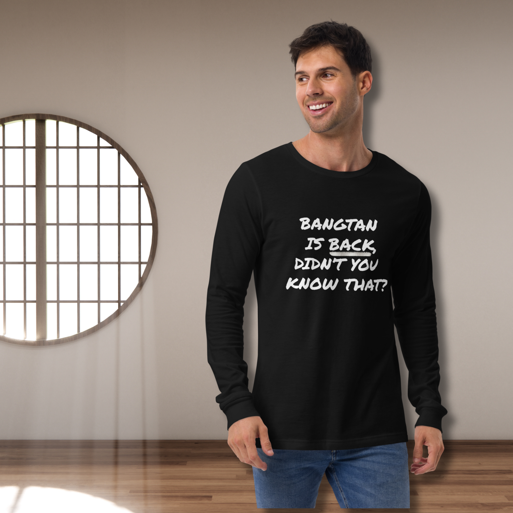 Man wearing a black long-sleeve shirt with text, standing in a room with a round window.  "Bangtan is Back, Didn't You Know That?"