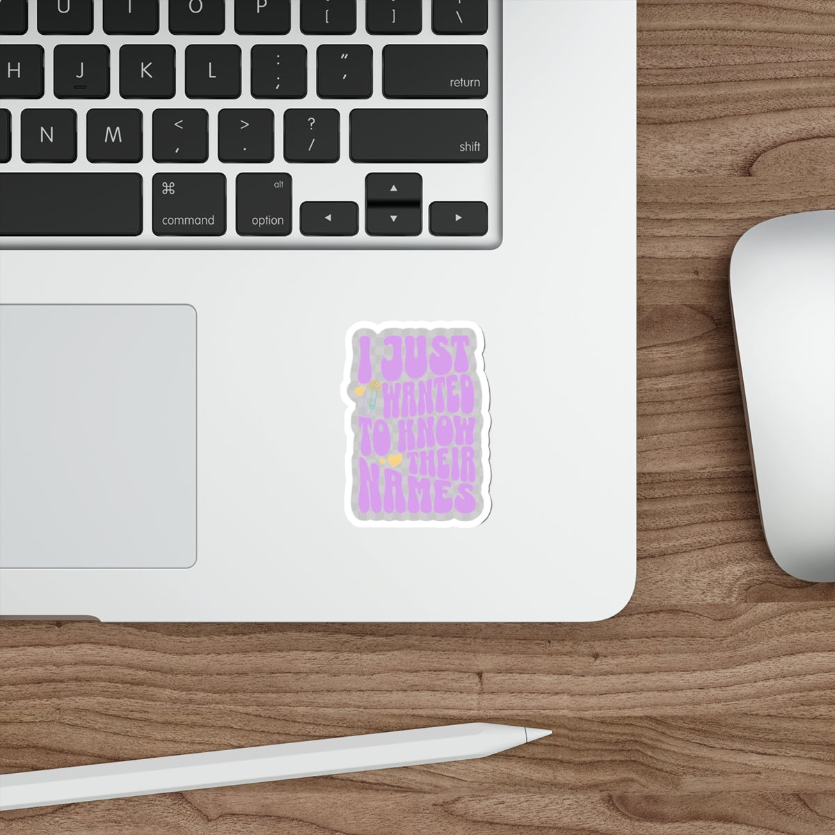 Laptop with a sticker on a wooden desk with a mouse and stylus. - clear sticker witih "I just wanted to know thier names" text, a few small hearts, and a microphone - subtle kpop fan merch