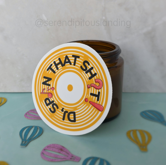 Brown jar with a colorful label on a light blue surface with decorative elements. - DJ Spin That Sticker | Serendipitous Landing