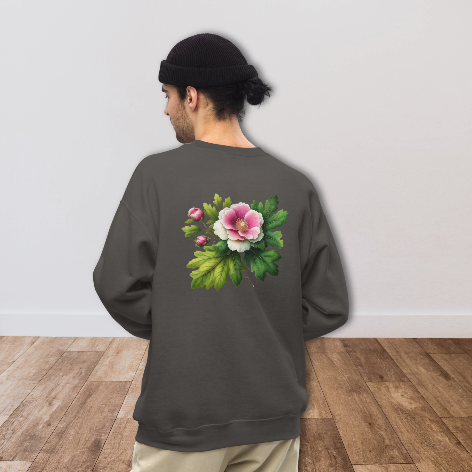 Person wearing a dark gray sweatshirt with a floral design on the back, standing against a plain white wall.  - mugunghwa and oak leaf botanical design - medium grey gray sweatshirt - [SAMPLE SALE] Mugunghwa & Oak Leaf Embroidered Sweatshirt (Unisex) | Serendipitous Landing