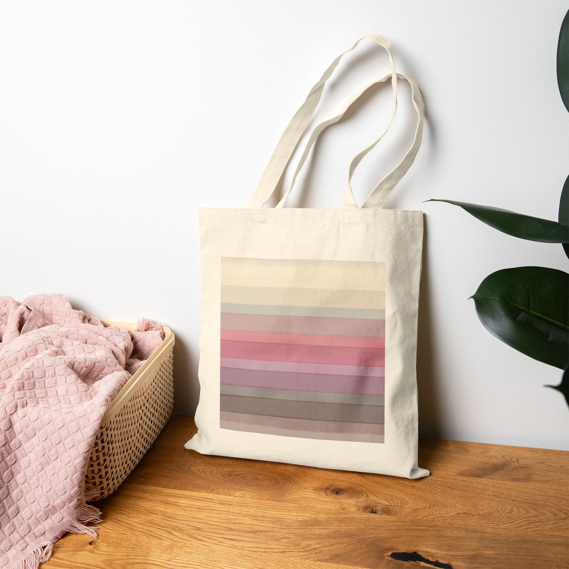Tote bag with a striped pattern (inspired by the BTS Arirang vinyl colors) on a wooden surface next to a basket and plant