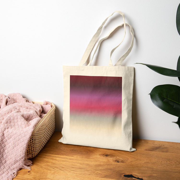 Tote bag with a gradient design (inspired by the BTS Arirang vinyl colors) on a wooden surface next to a basket and plant