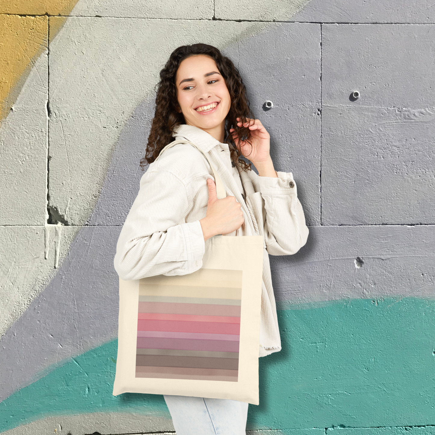 Woman holding a tote bag with color swatches (inspired by the BTS Arirang vinyl colors) against a textured wall.