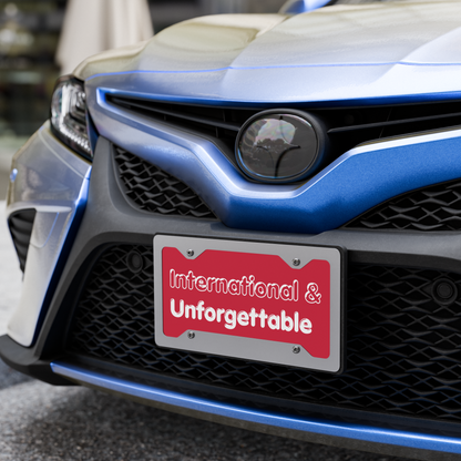 Close-up of a car's front grille with a red license plate reading 'International & Unforgettable'. - Laureles Internacionales Vanity License Plate - Serendipitous Landing