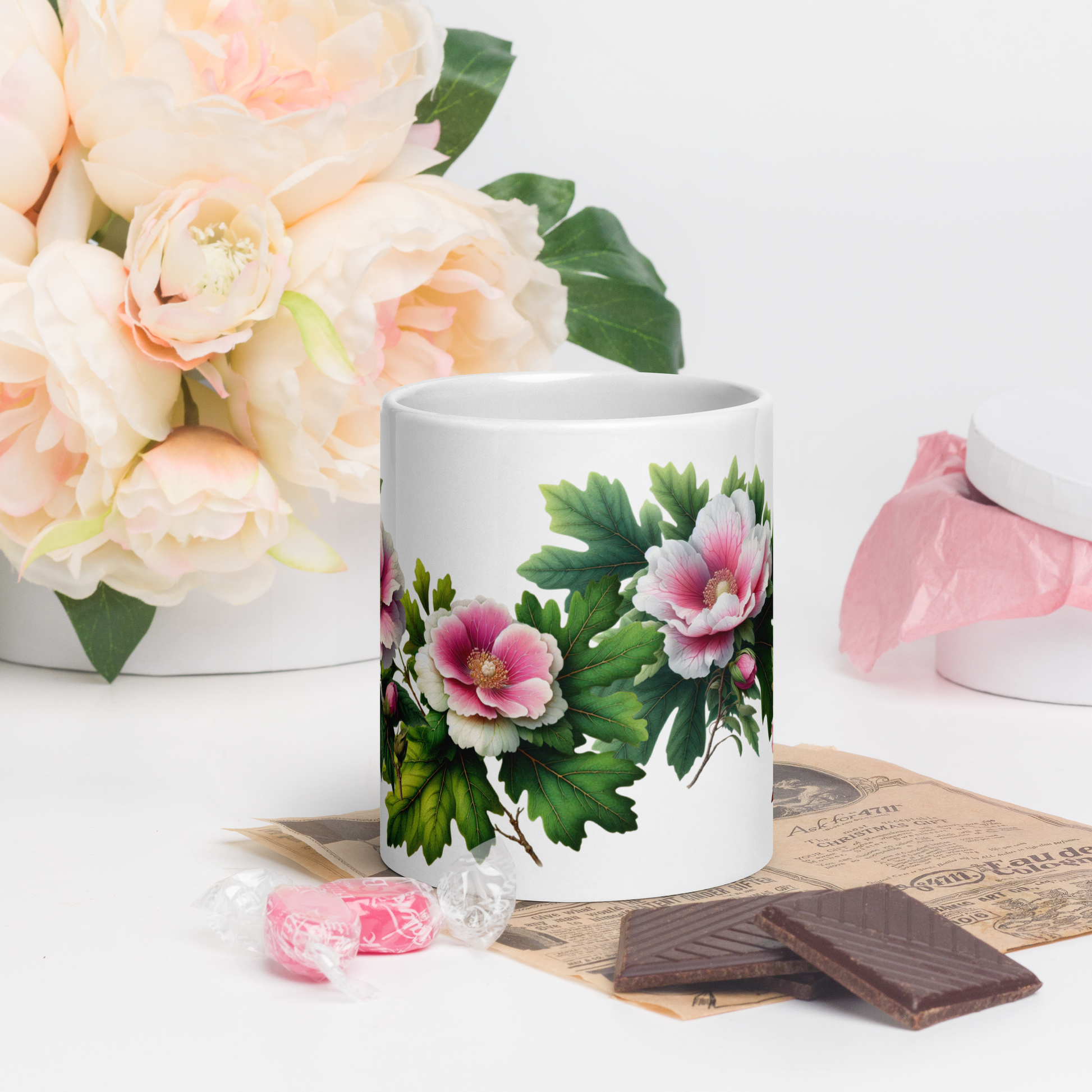 White mug with floral design on a table with flowers and chocolates. - mugunghwa and oak leaf botanical design - 20 oz ceramic mug